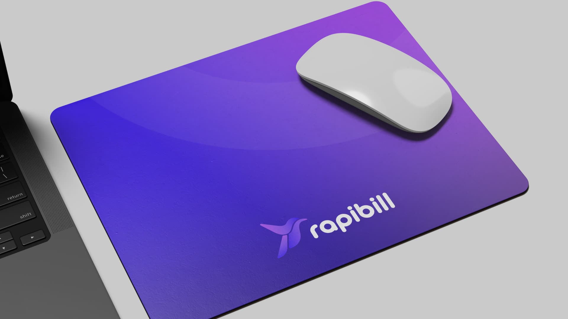Rapibill mouse pad in a violet gradient next to a laptop
